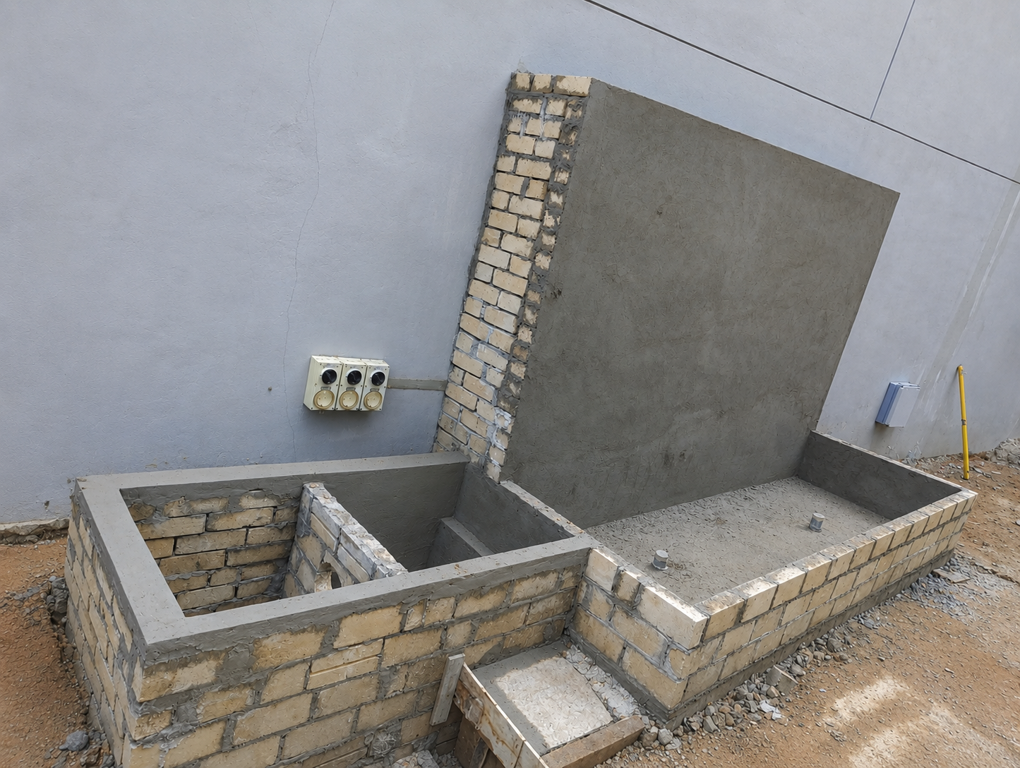 Before — bare brick and rendered concrete shell of a waterfall wall and pond under construction in a side courtyard, by GP FloraL in Penang