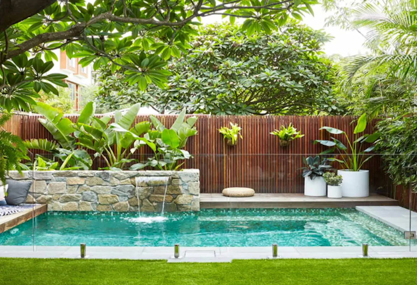 Resort poolside tropical landscaping in Penang with a stone water feature and lush planting, by GP FloraL